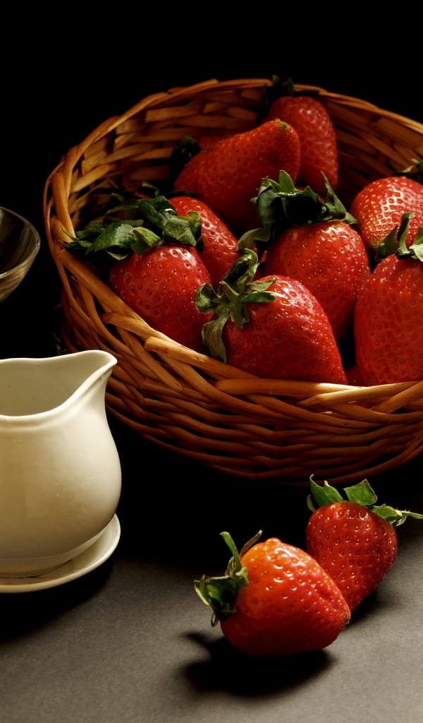 Корзина со спелой красной клубникой на столе с посудой