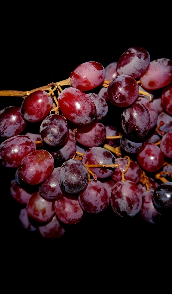 Гроздь розового винограда на черном фоне