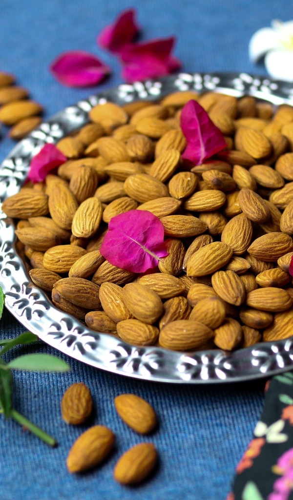 Вкусные миндальные орехи на тарелке с цветами
