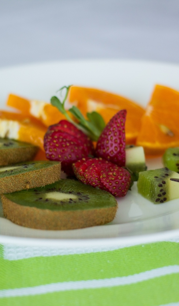 Свежие нарезанные фрукты на тарелке с вилкой