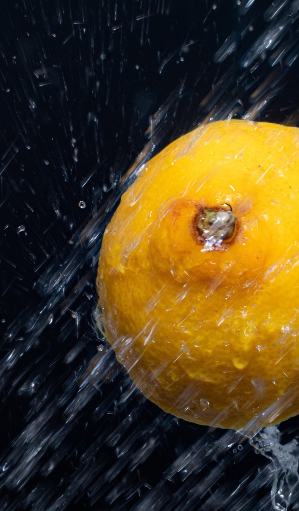 Лимон в брызгах воды на черном фоне