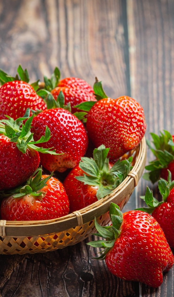 Много спелой красной клубники в деревянной посуде 