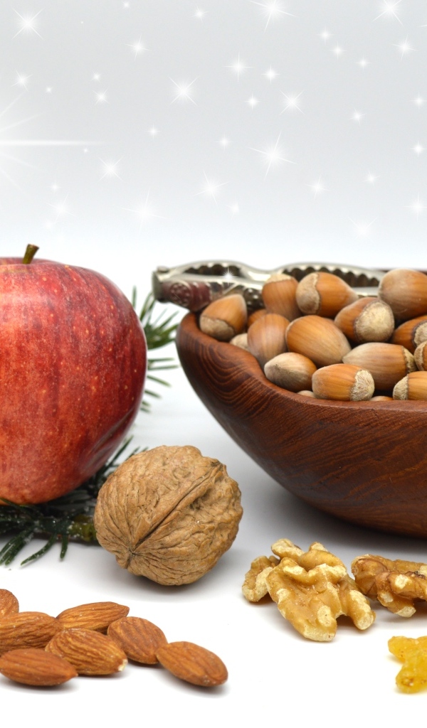 Орехи с яблоком и еловой веткой на столе
