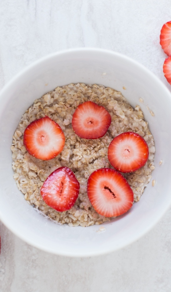 Овсяная каша с клубникой в белой тарелке 