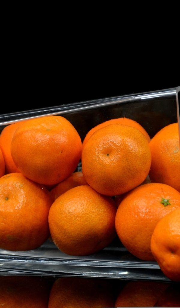 Оранжевые мандарины в стакане на черном фоне