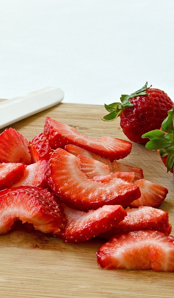 Красная клубника нарезана на деревянной доске