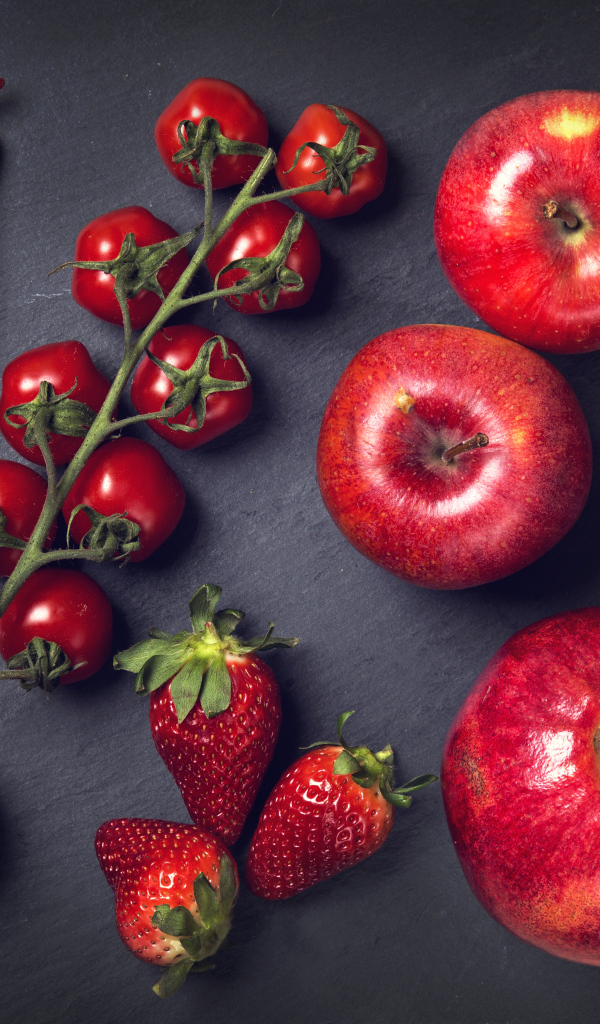 Красные овощи и фрукты на сером столе