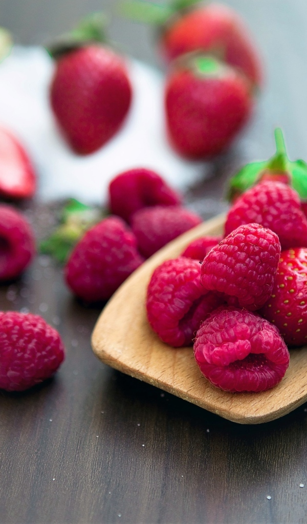 Спелая красная малина с деревянной ложкой на столе