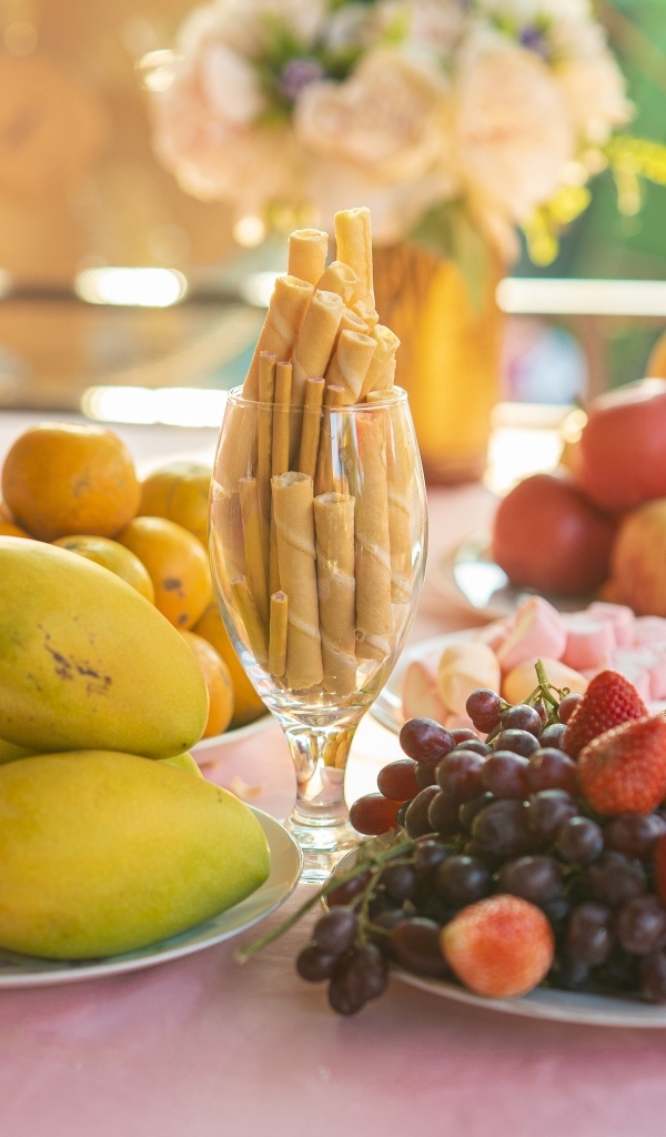 Спелые сладкие фрукты и ягоды на столе с трубочками