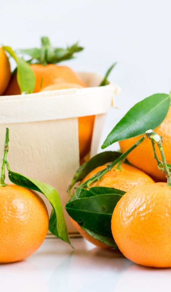 Спелые сладкие мандарины с корзиной на столе