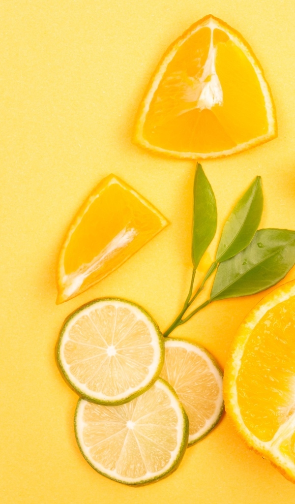 Нарезанные плоды апельсина и лайма на желтом фоне