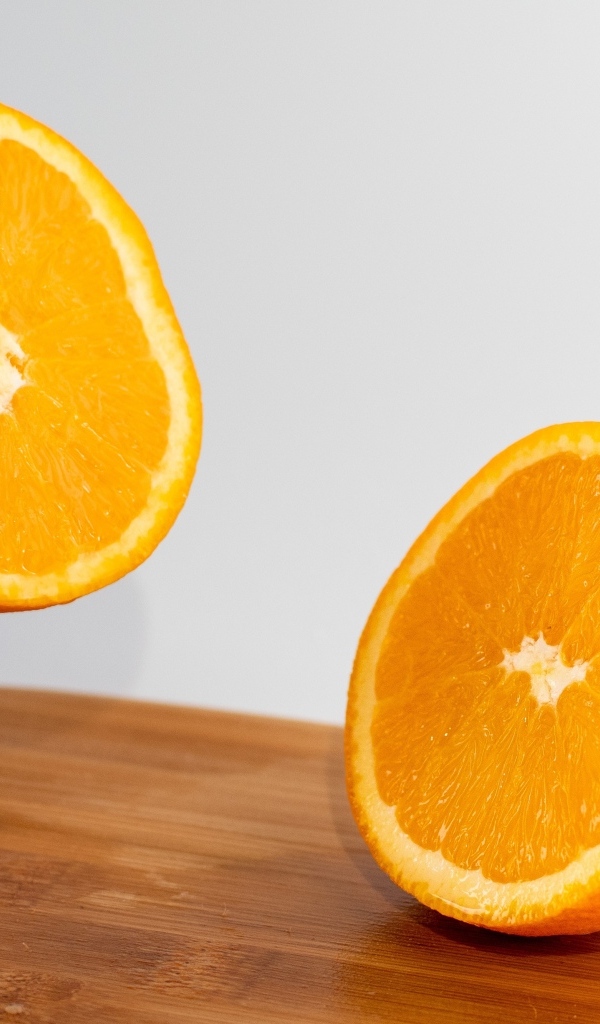 Две половинки апельсина на деревянной доске