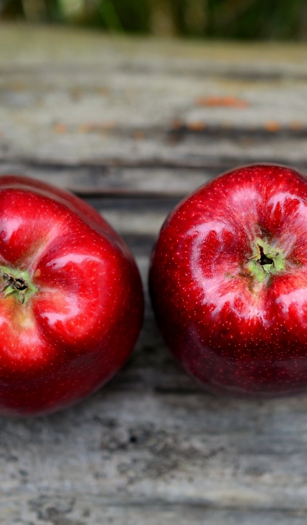 Два красных яблока на деревянном столе