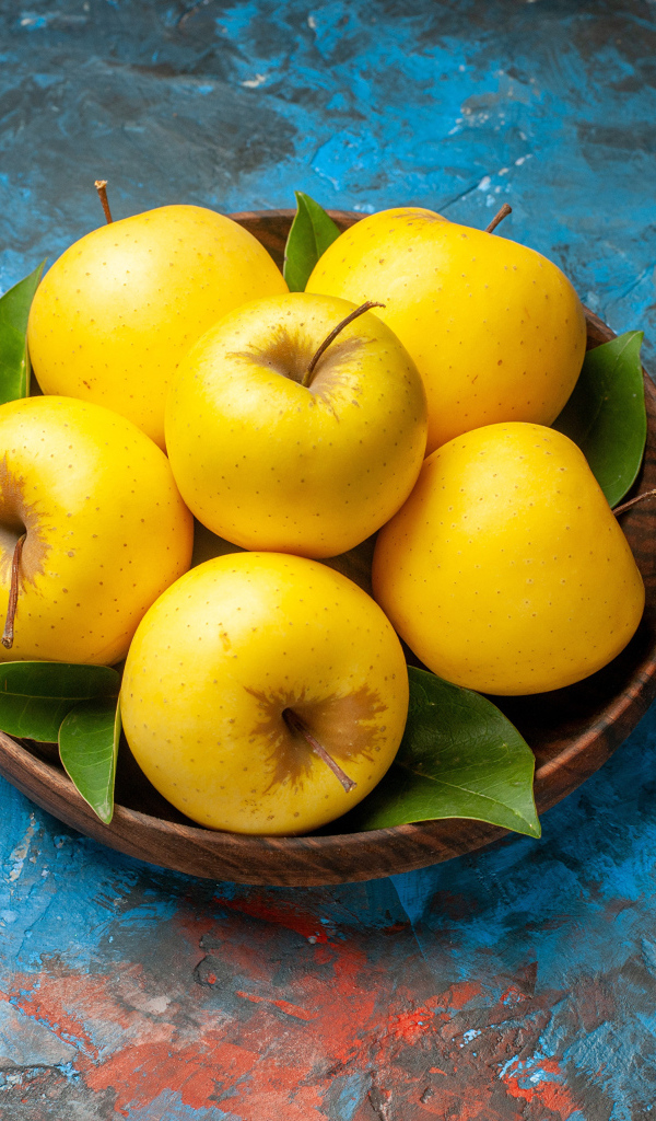 Деревянная тарелка с яблоками на столе