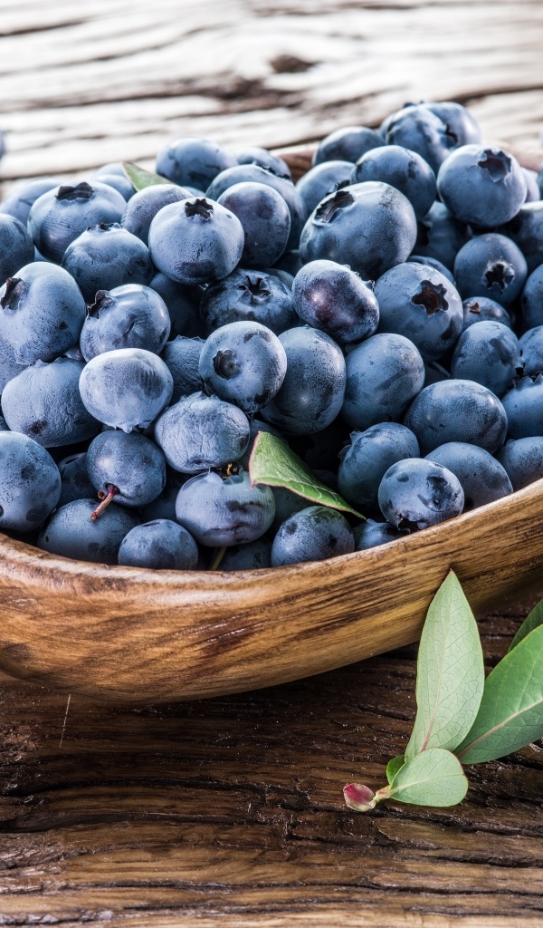 Деревянная тарелка с ягодами черники на столе