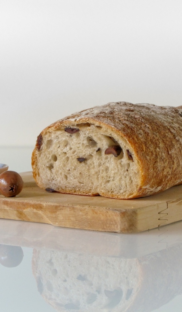 Свежий хлеб с оливками на разделочной доске