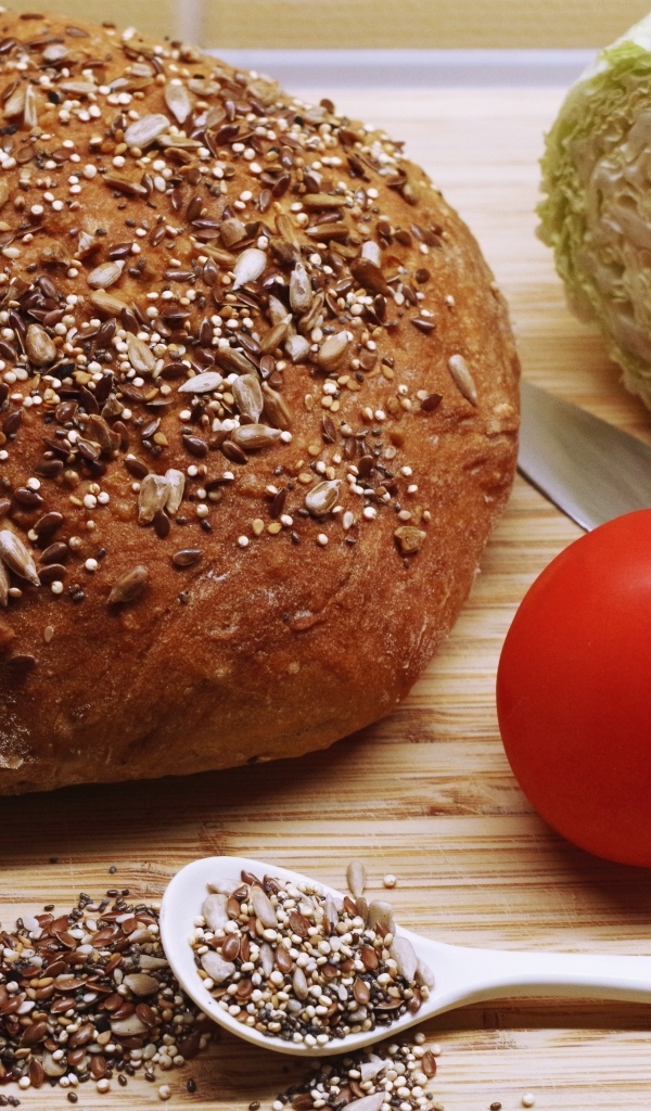 Буханка хлеба на столе с капустой и помидором