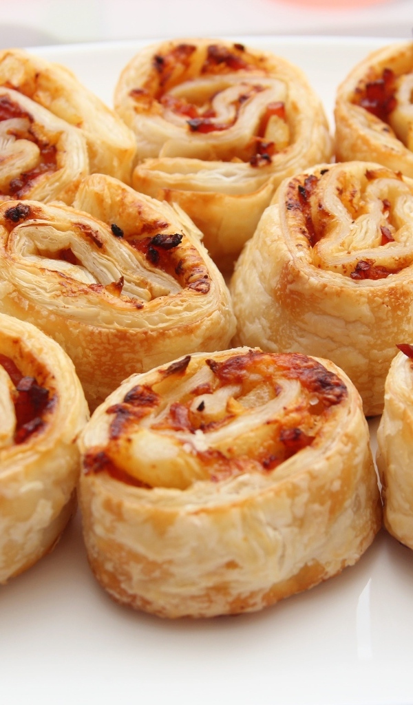 Рулетики из слоеного теста с ветчиной на тарелке