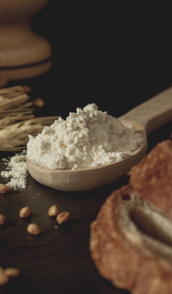 Ложка муки на столе с пшеницей и хлебом