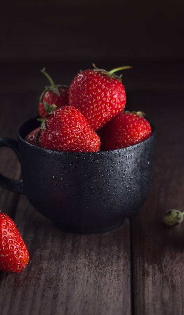 Черная чашка с красными ягодами клубники