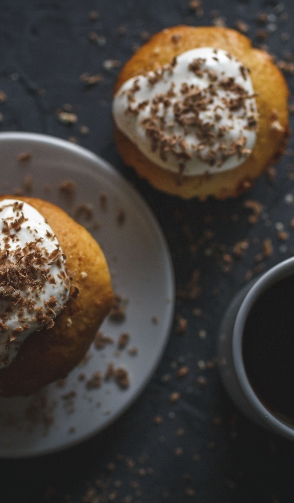 Пирожное в тертым шоколадом на столе с чашкой кофе