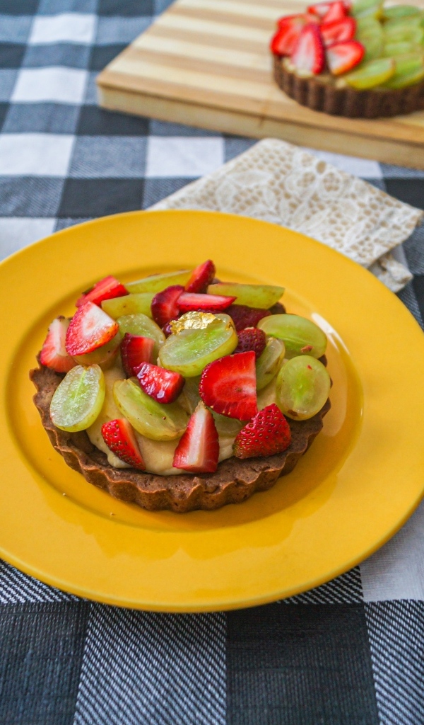 Пирожное с кремом и ягодами клубники и винограда