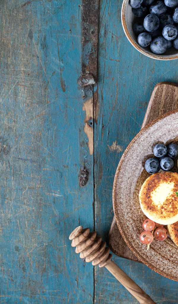 Сырники с ягодами черники на тарелке с медом