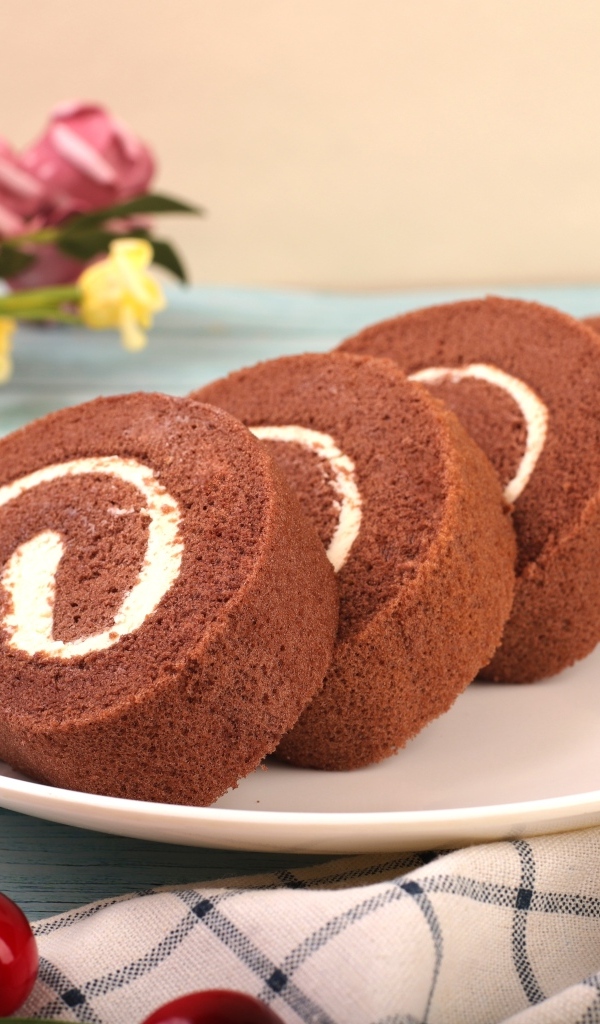 Шоколадный бисквитный рулет с кремом на тарелке