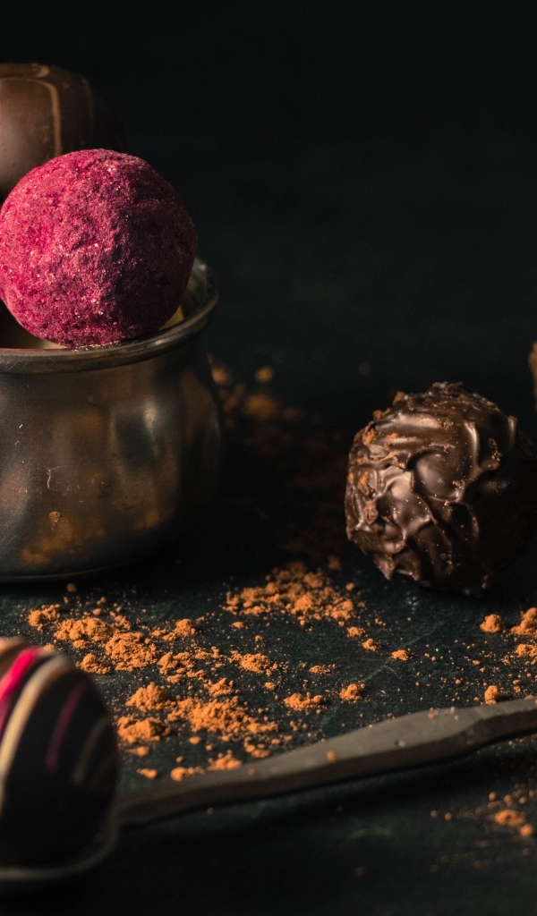 Шоколадные конфеты с железной чашкой на черном фоне