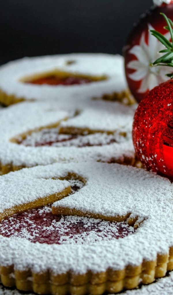 Вкусное сладкое печенье в сахарной пудре на столе с елочными игрушками