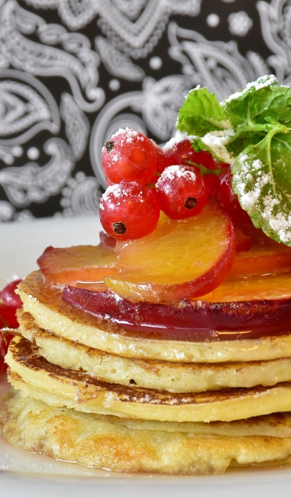 Оладьи на тарелке с ягодами смородины  и сливы