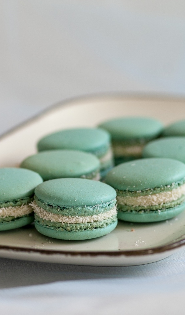 Зеленый десерт макаронс на большой тарелке на столе