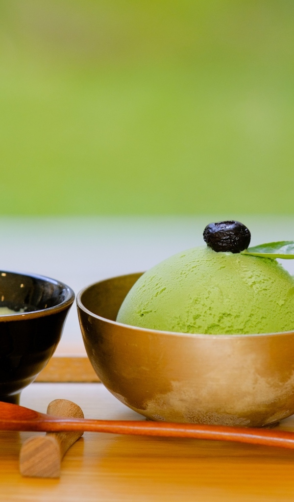 Зеленый шарик мороженого в чашке на столе