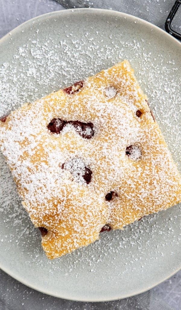 Кусок вишневого пирога на тарелке с сахарной пудрой