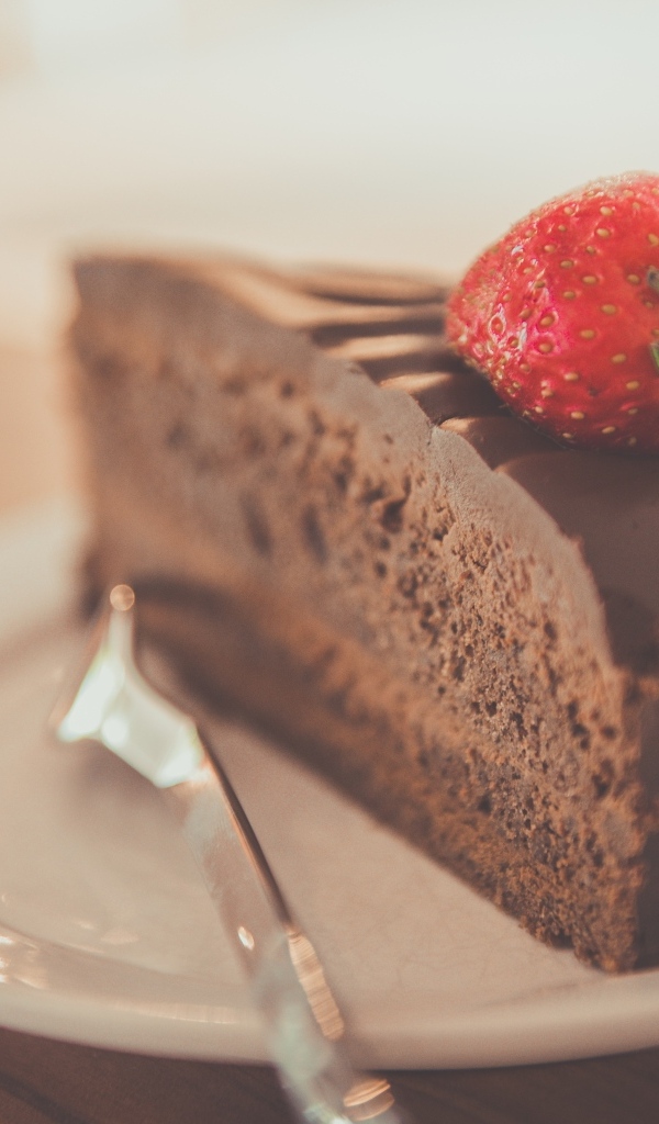 Кусок шоколадного торта с клубникой на тарелке