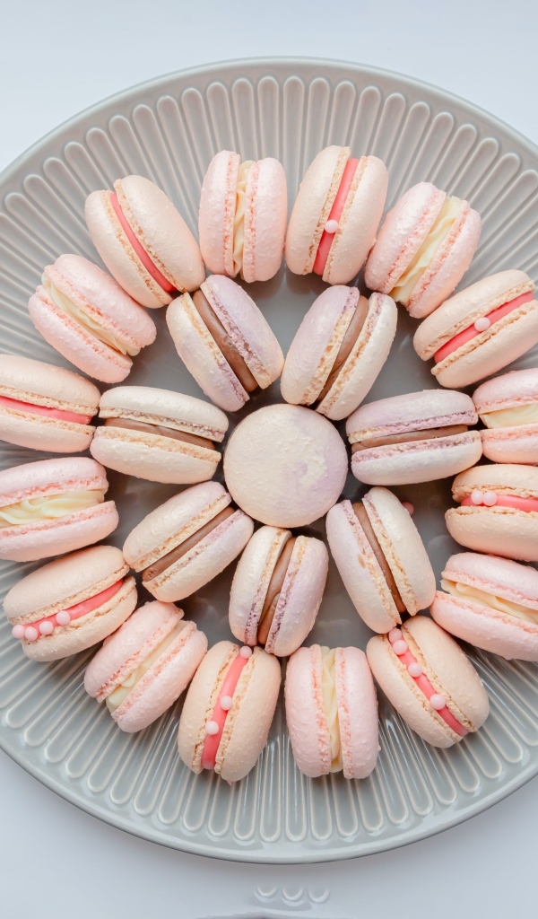 Розовый десерт макарон на большой тарелке