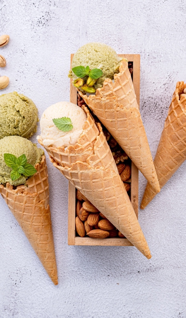 Фисташковое и сливочное мороженое с рожками на столе 
