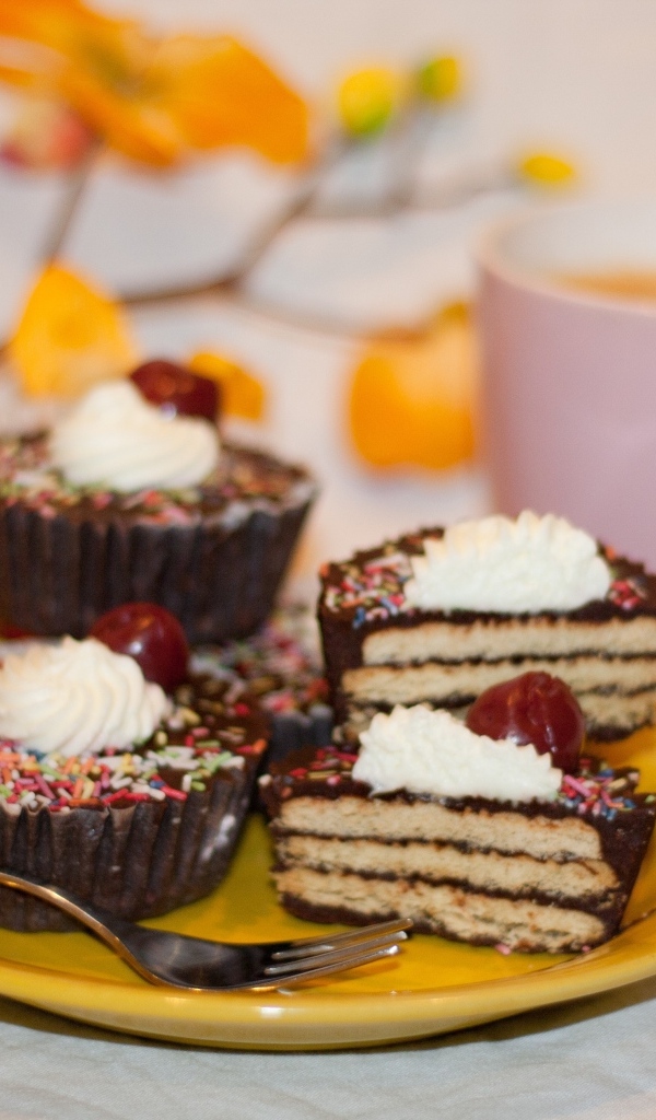 Сладкие вкусные пирожные на столе с чашкой чая и цветами