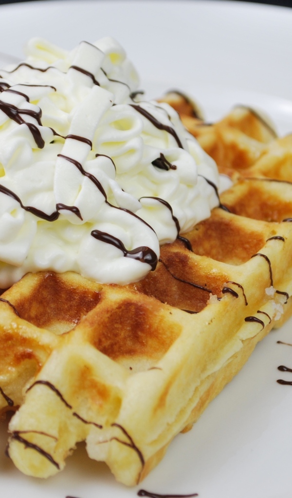 Сладкая вафля со сливками на белой тарелке