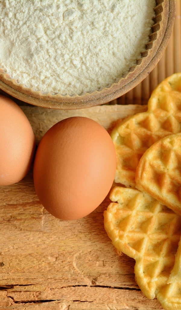 Сладкие вафли с яйцами и мукой на столе