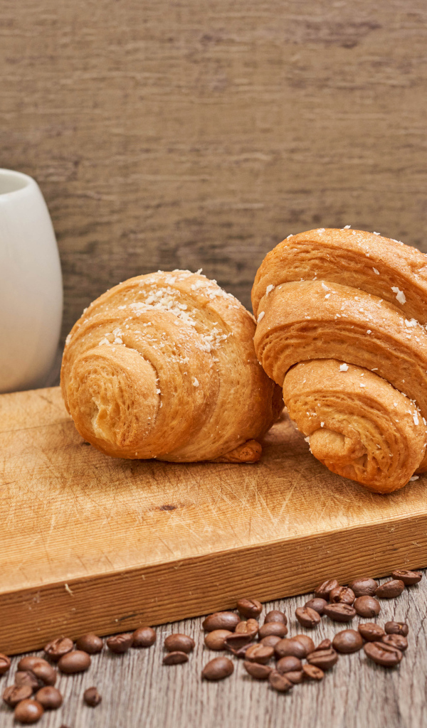 Два круассана на доске с кофейными зернами