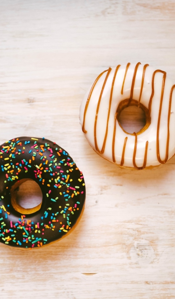 Два пончика в глазури на деревянном столе