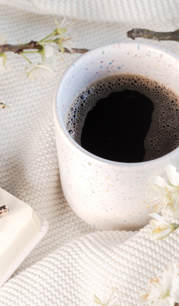 Чашка кофе с цветущей веткой на столе