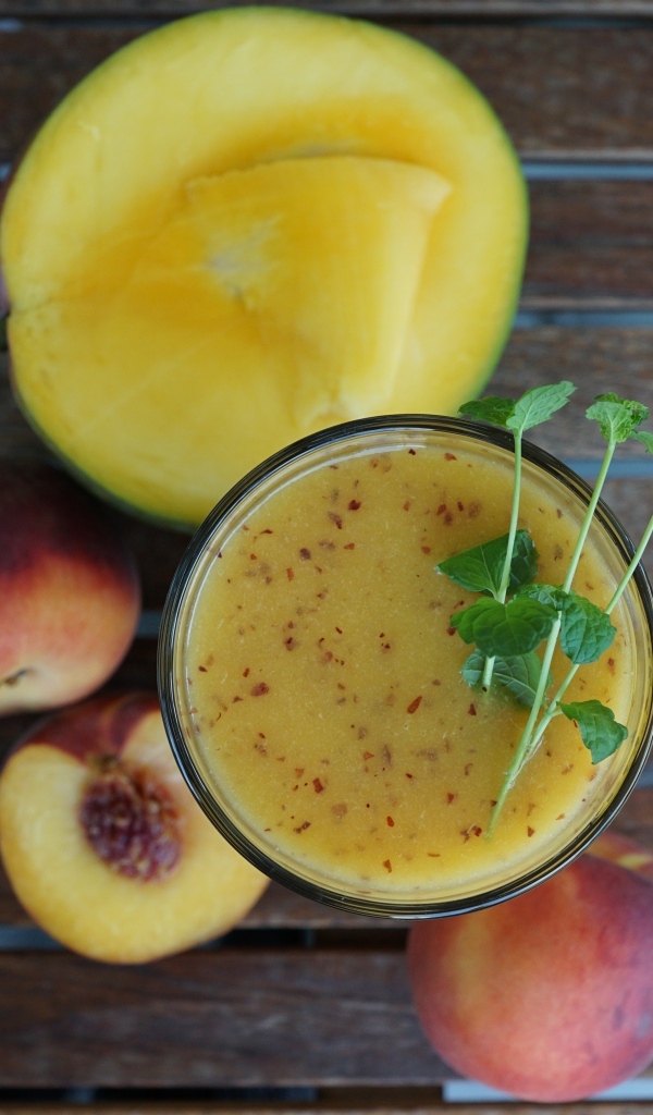 Коктейль с веточкой мяты на столе с фруктами