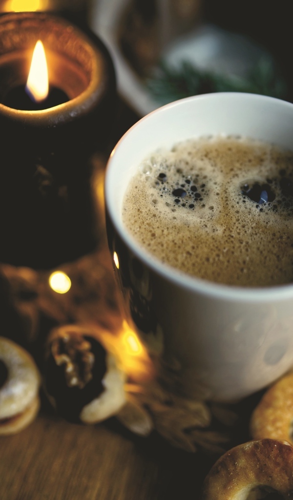Чашка кофе на столе со свечой и печеньем