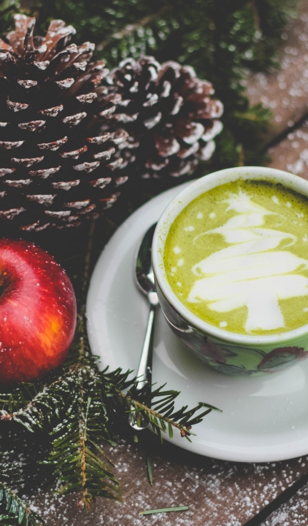 Чашка кофе на столе с яблоками и шишками