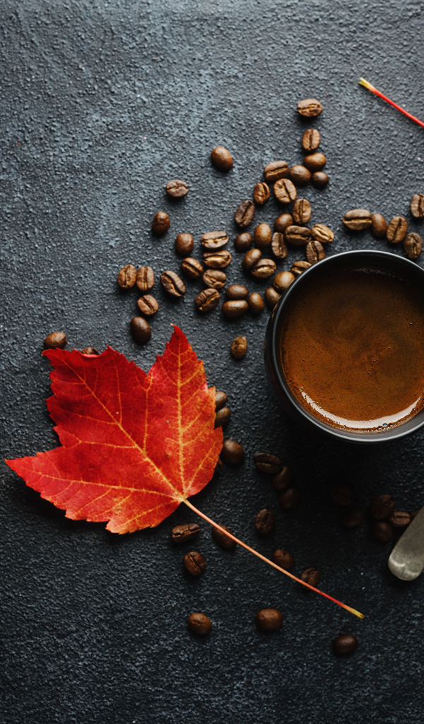 Чашка кофе на столе с зернами и желтыми листьями