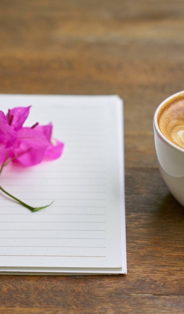 Чашка кофе на столе с блокнотом и цветами