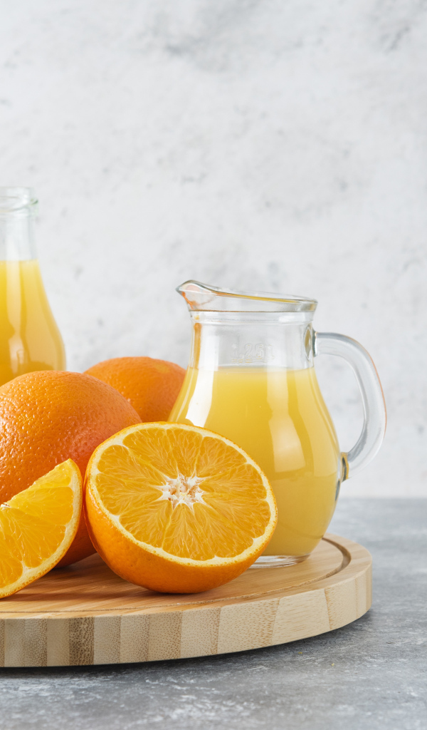 Свежевыжатый сок на столе с апельсинами