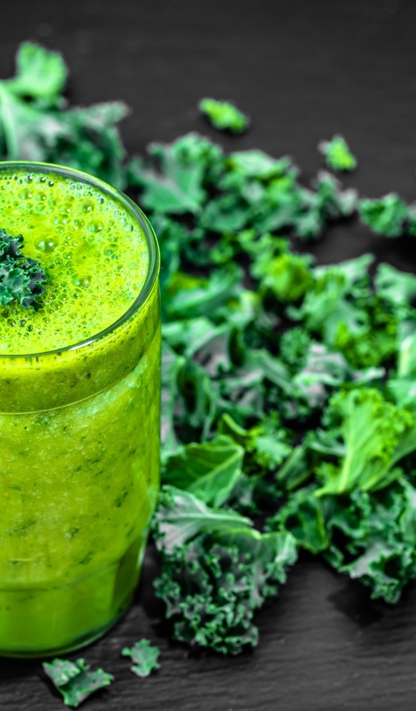 Бокал с зеленым смузи с листьями